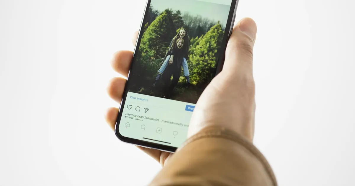A person holding a black smartphone, about to share something