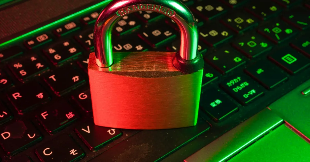 A padlock resting on a laptop keyboard, lit from the side against a dark background.